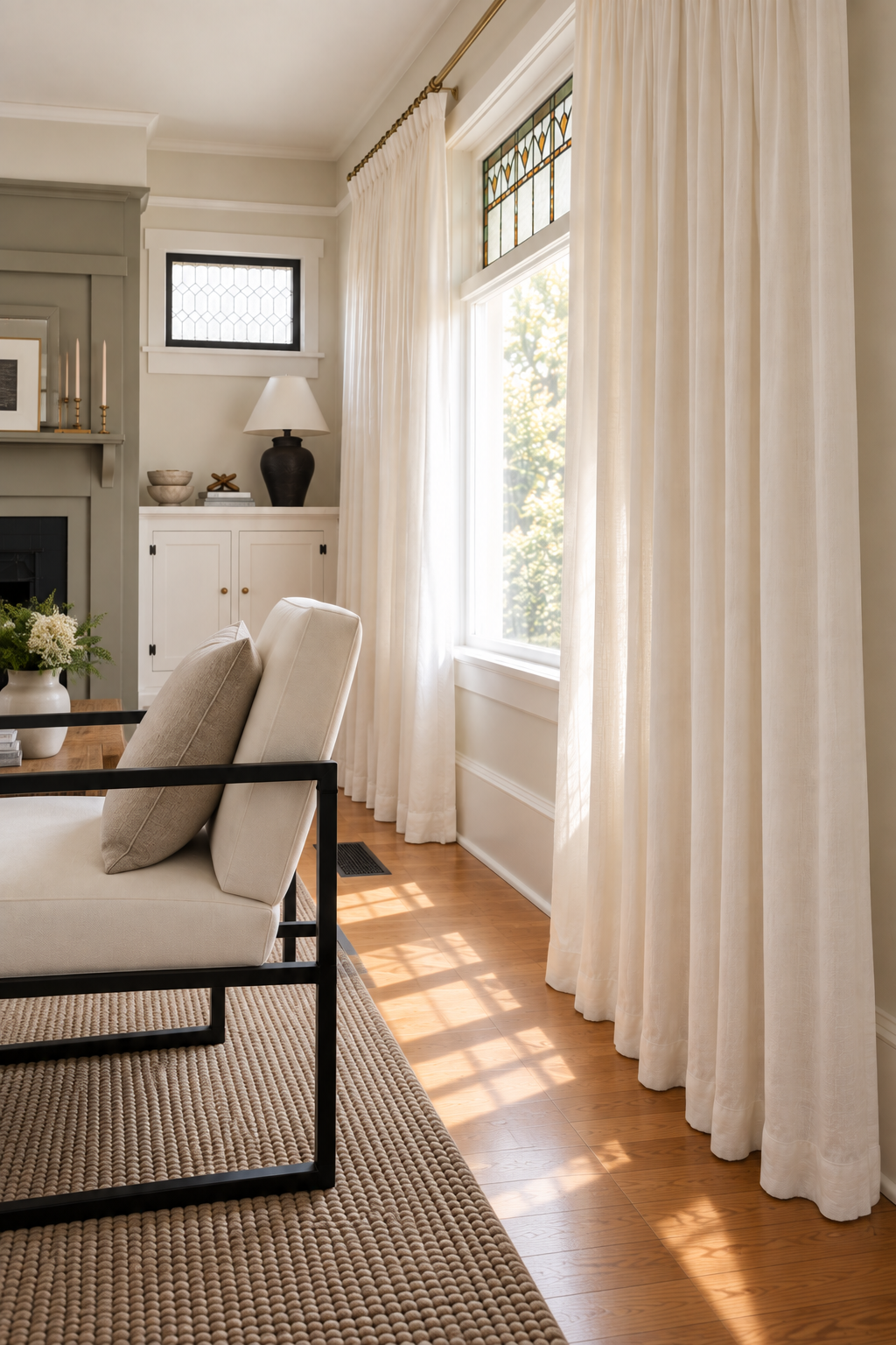 White custom-look curtains framing a stained-glass living room window